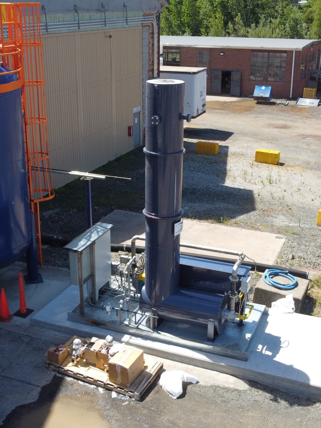 Vertical industrial incinerator with piping and valves in an outdoor yard